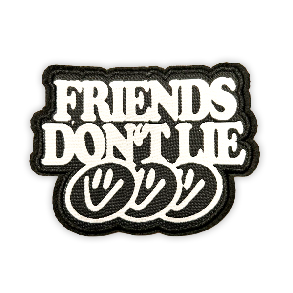 Ein schwarz-weißer, bestickter Aufnäher zeigt den zweizeiligen Schriftzug „FRIENDS DON’T LIE“ in großen, weißen Blockbuchstaben. Darunter befinden sich drei überlappende, minimalistisch gezeichnete Smiley-Gesichter auf schwarzem Hintergrund.